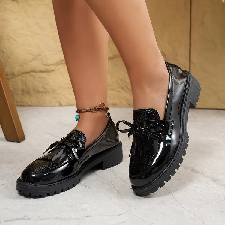 Women's black flat loafers with a decorative bow on the upper, made from artificial PU leather.