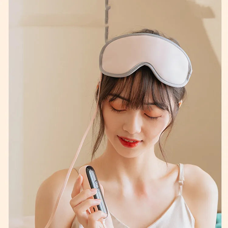 Pink portable eye steam massage goggles with USB cable on a grey background.