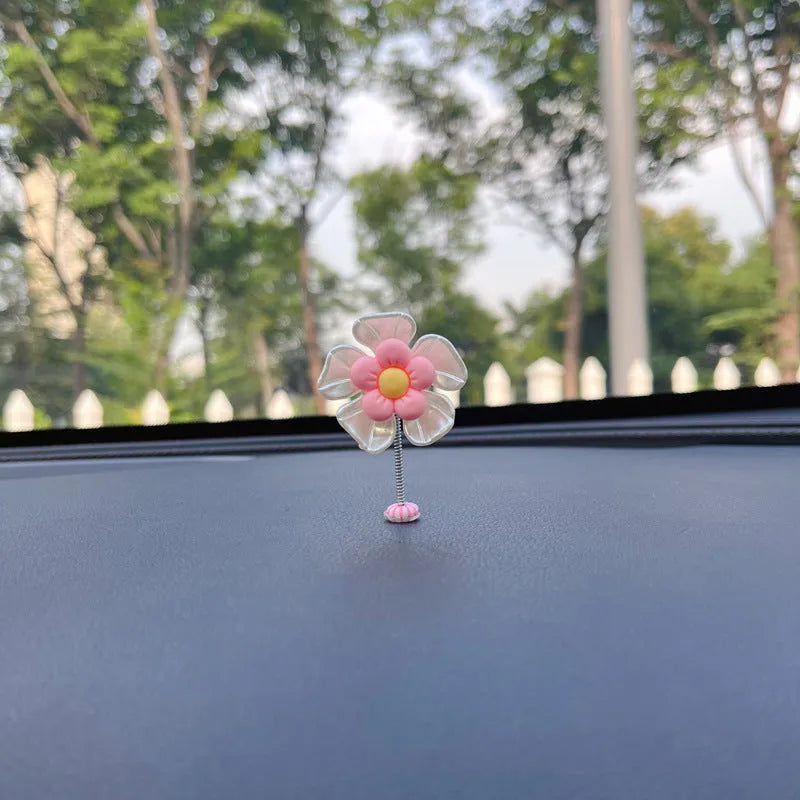 Small colourful plastic car decoration shaped like a swing, shown in blue, on a car dashboard.