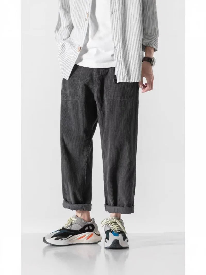 Man wearing loose tapered straight-leg trousers in a dark grey colour with wide legs.