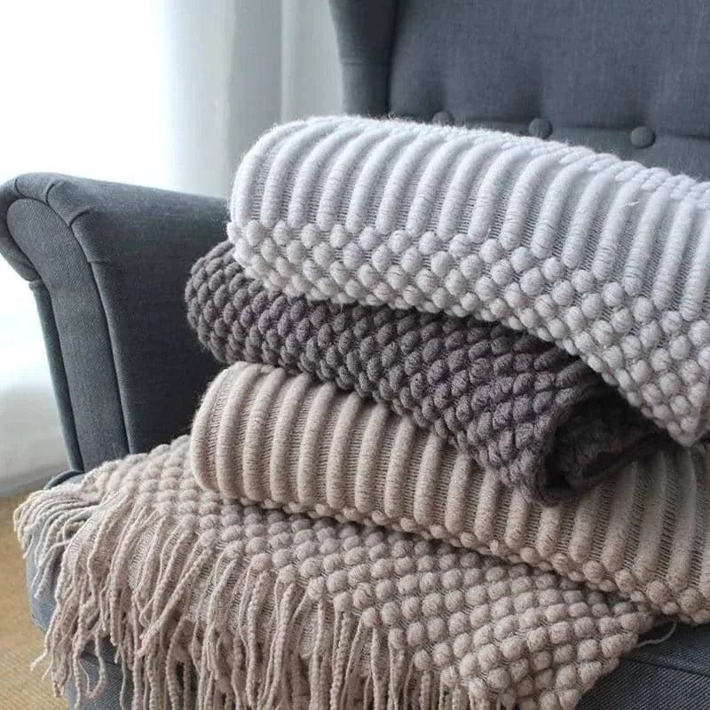 Small light grey polyester fleece blanket folded on a sofa