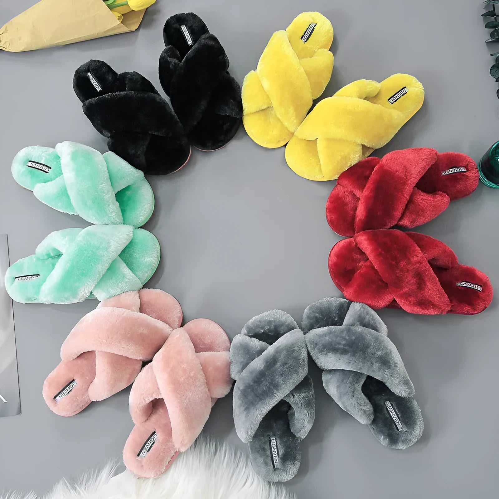 Women's black cross open-toe fur slippers on a white background, showing criss-cross upper and patterned sole.