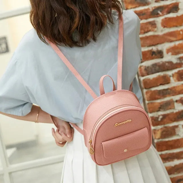 Small black PU women's shoulder backpack with zipper, shown next to a mobile phone for scale.
