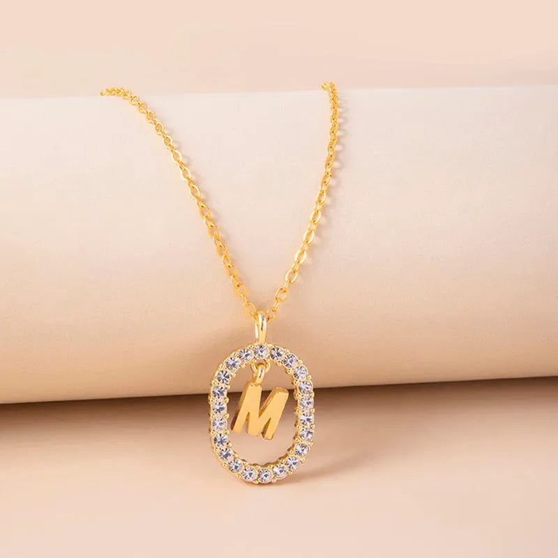 Gold crystal letter necklace with rhinestone initial on oval pendant and O-chain