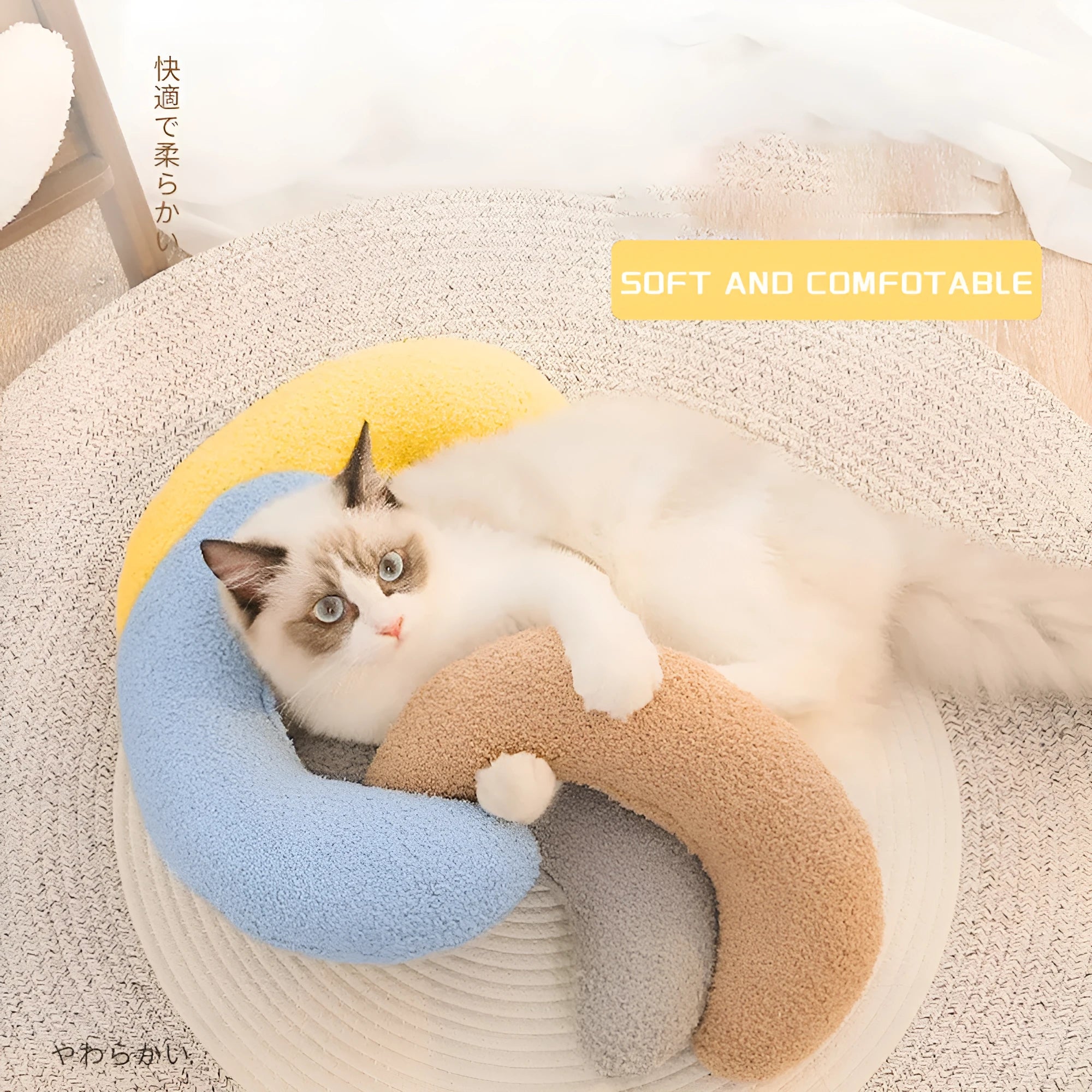 Blue U-shaped cat pillow with a white adjustable padded collar on a grey sofa.