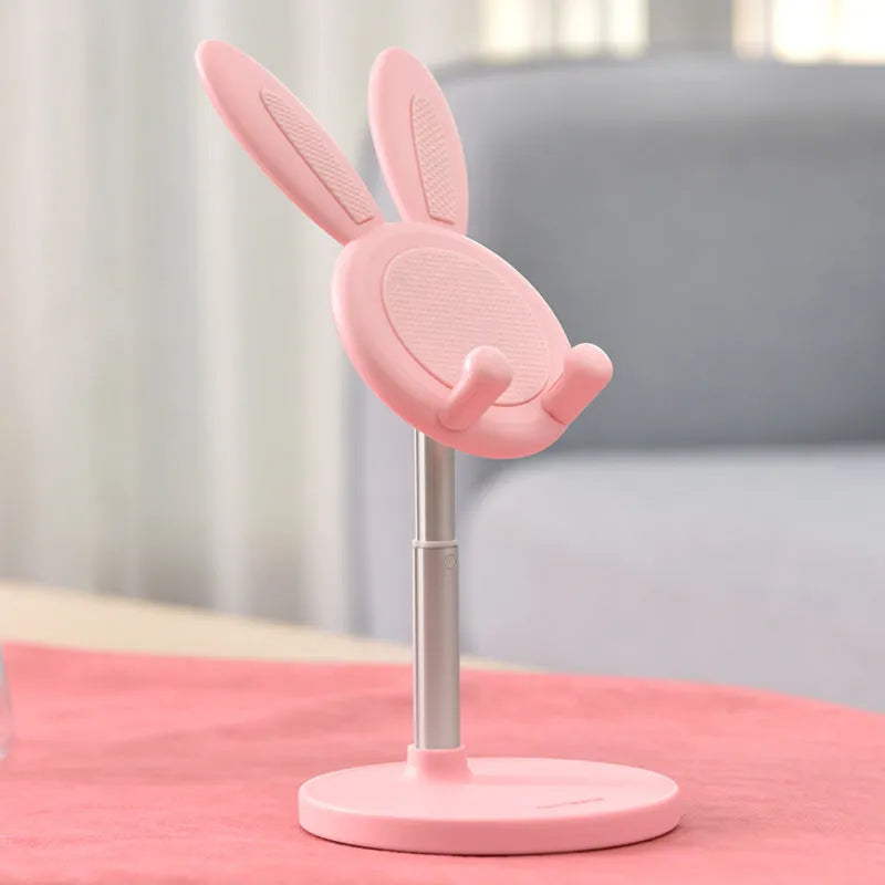 Rabbit-shaped silicone phone stand in pink on a desk with a mobile phone