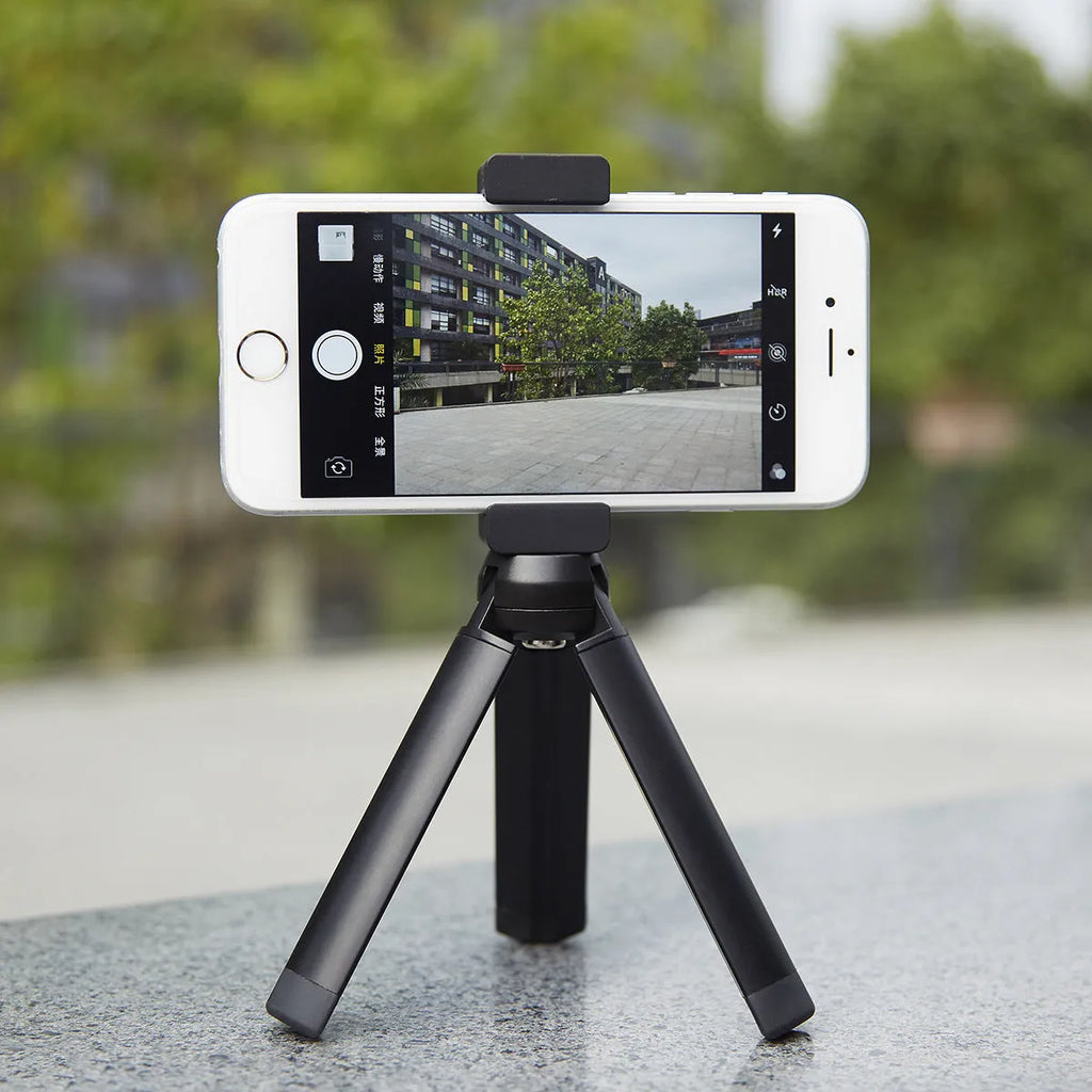 Silver aluminium alloy phone bracket for iPhone shown in clip and tripod style next to a mobile phone.