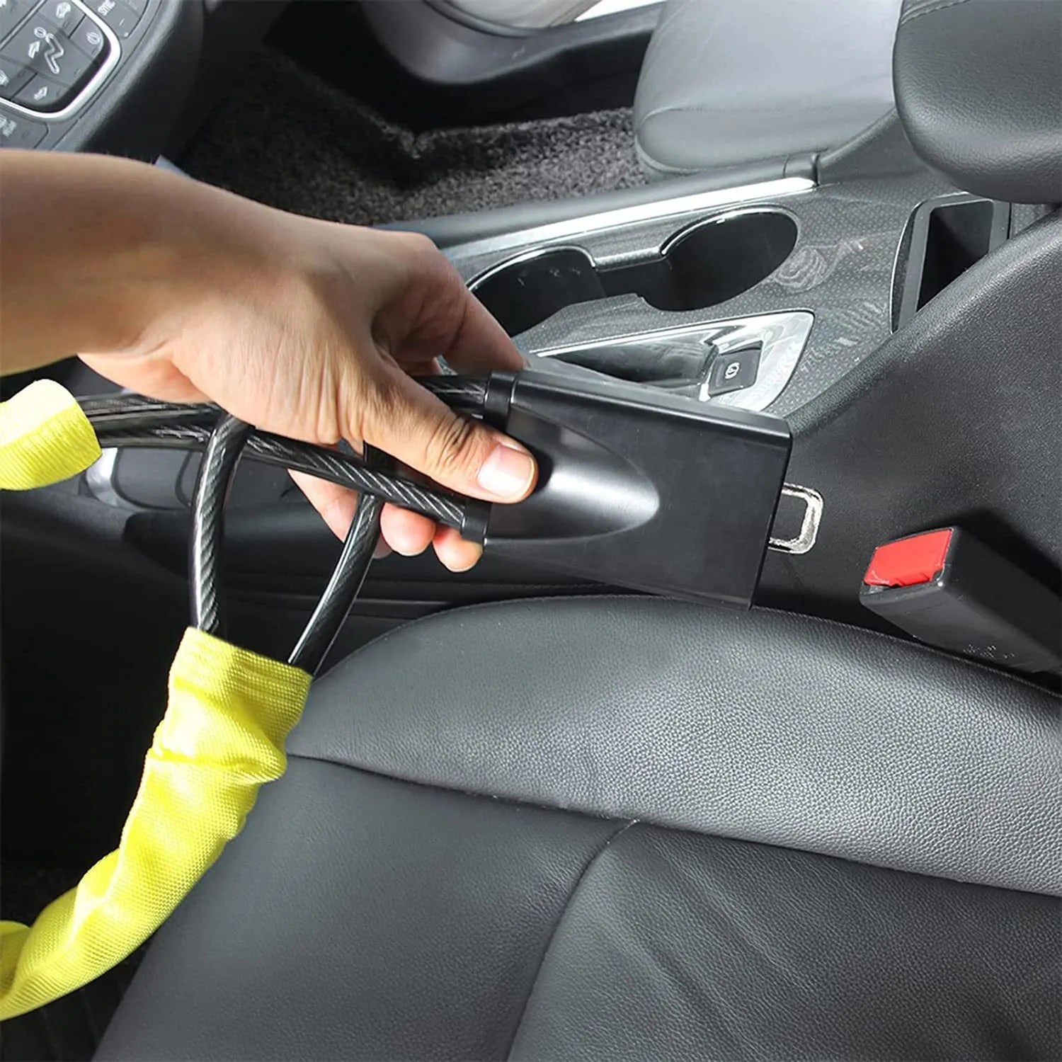 Red steel car steering wheel security lock with coiled cable on a car seat.