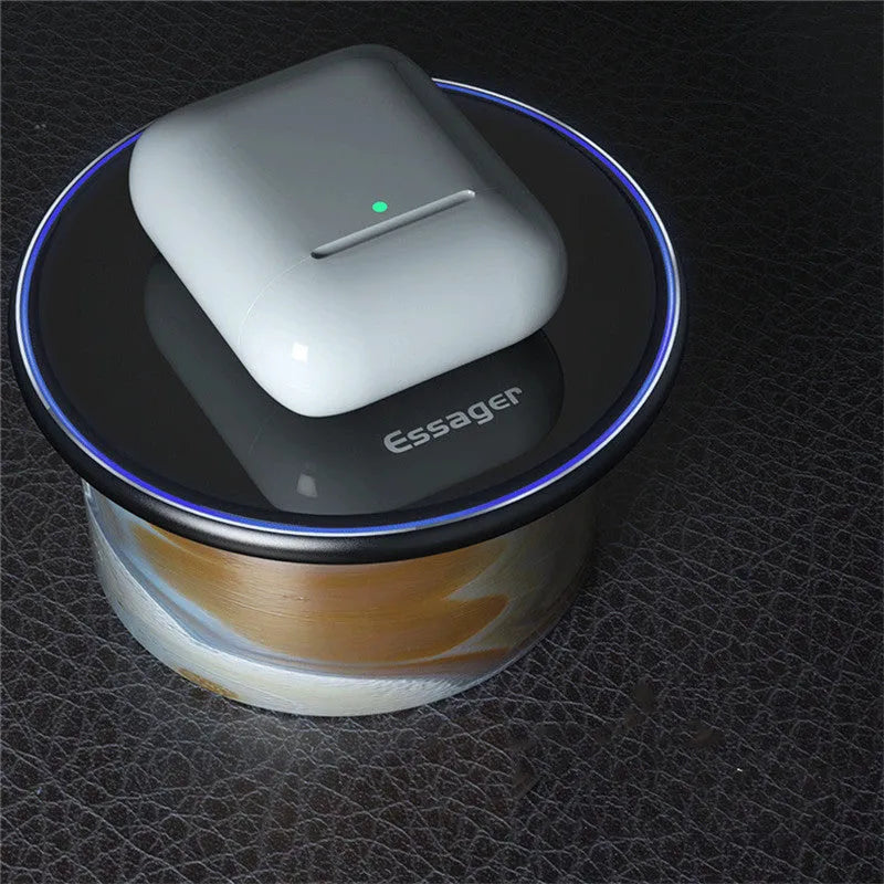 Black aluminium wireless charging pad on a desk with a mobile phone charging on top.