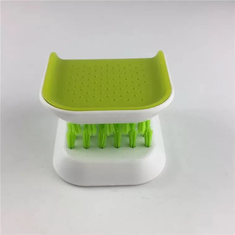 Blue U-shaped plastic brush for cleaning kitchen knives and forks on a draining board.