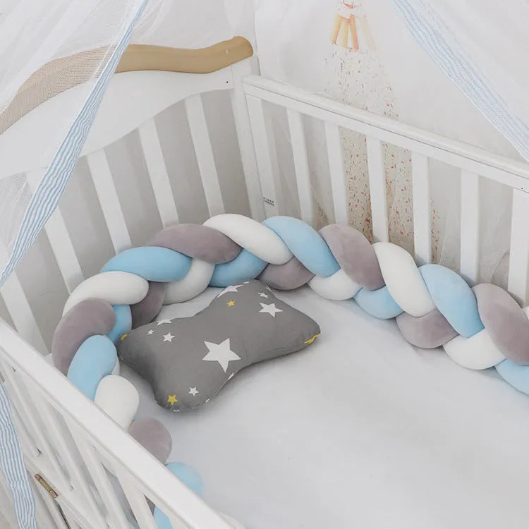 Braided knot style crib bumper in spandex velvet, wrapped around white cot rails in a nursery.
