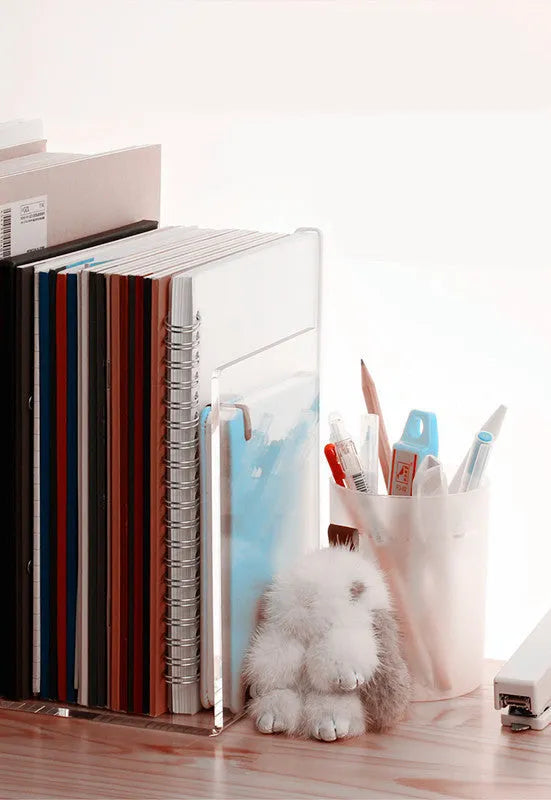Clear transparent acrylic bookshelf holding a small stack of books on a desk.