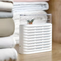 White recyclable cabinet dehumidification box with transparent geometric top cover showing colour-changing silica gel inside.