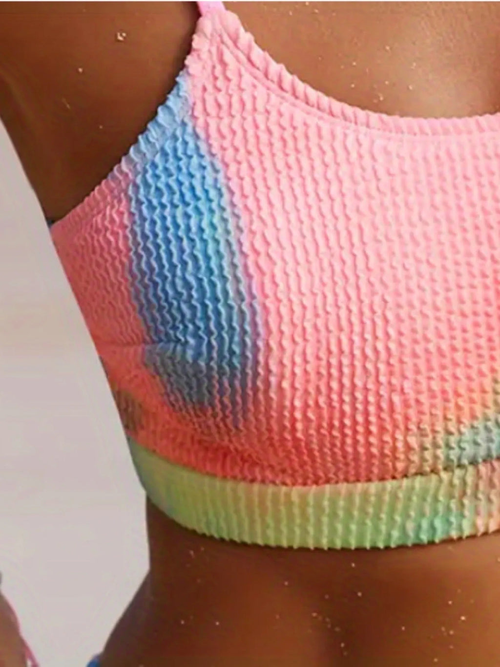 Women's orange and blue tie-dye pleated bikini set on a white background.