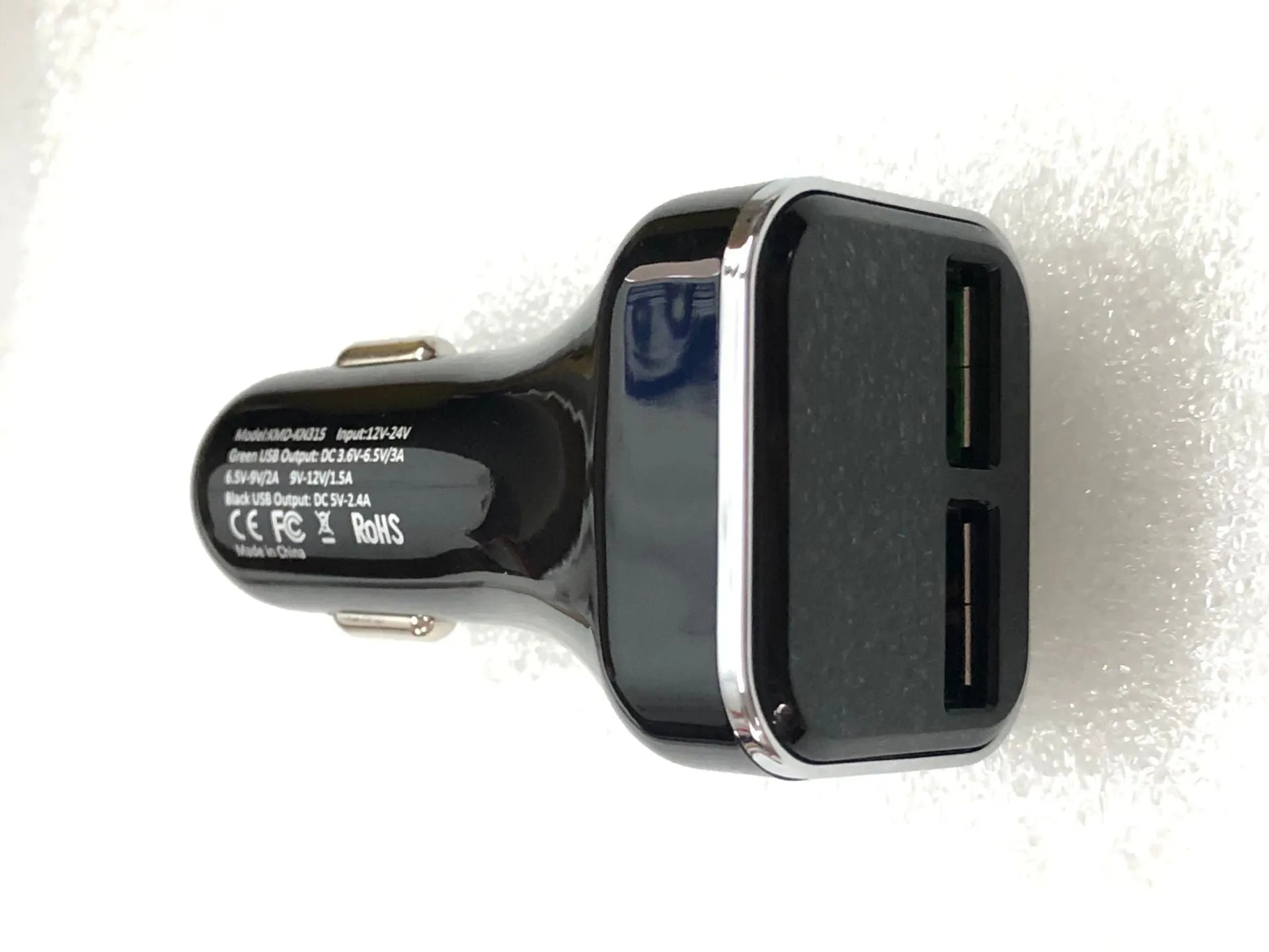 Black dual USB car charger with LCD screen displaying voltage, plugged into a car dashboard socket.