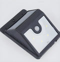 Tall outdoor solar light with four LEDs and an adjustable panel on a pole in a garden