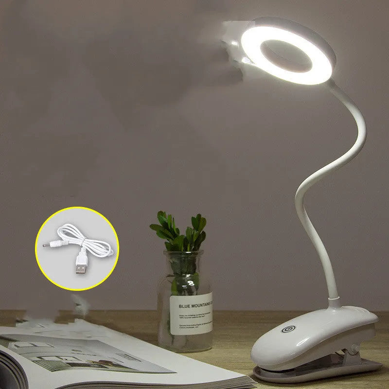 Modern clip-on rechargeable LED desk lamp with touch switch and plastic shade in use on a desk.