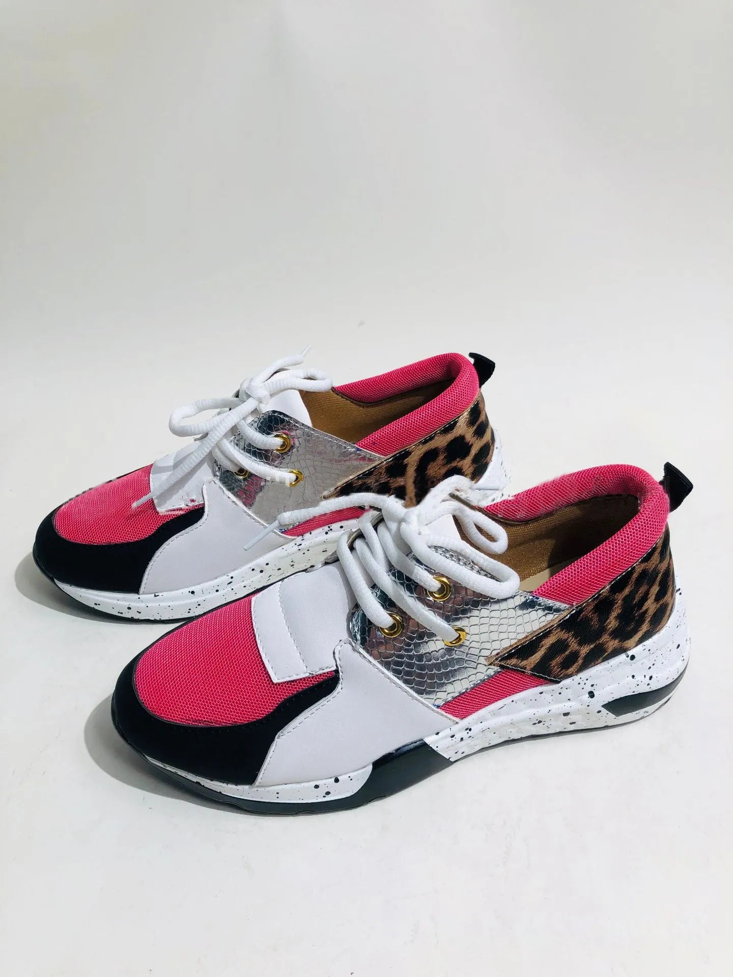 Women's black suede wedge sneakers with a low-cut ankle and round toe on a wooden floor.