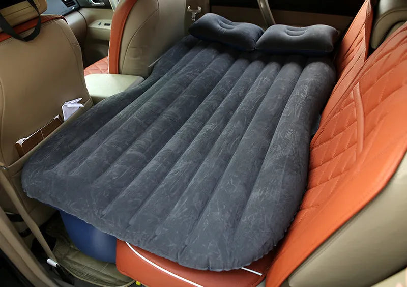 Black car inflatable bed with two pillows, shown inflated in a vehicle's rear compartment.