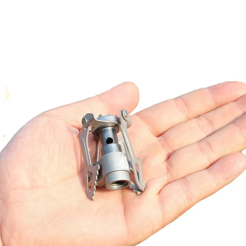 Compact one-piece propane camping stove on a rocky outdoor surface.