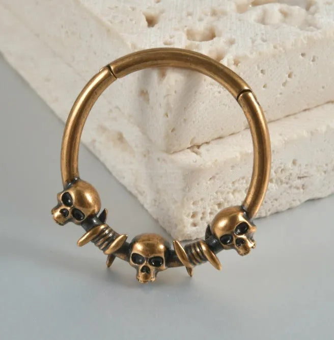 A pair of vintage-style copper earrings with an embossed ghost head design on a stud post, showing an antique silver finish.