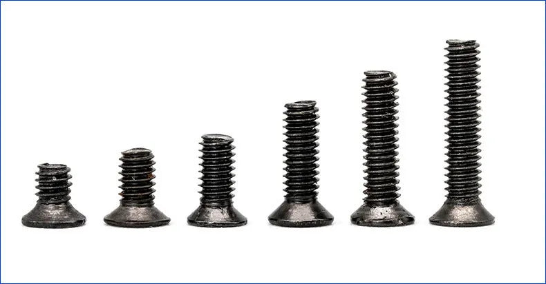 Black flat head M1.4 x 16mm laptop screws spilt from a box, showing cross slot drive and countersunk head profile.