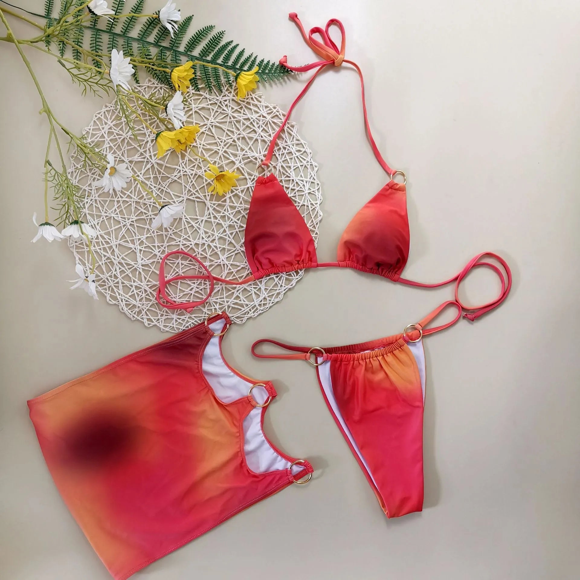 Women's tie-dye gradient halter neck bikini top and skirt three-piece swimsuit set on a beach background