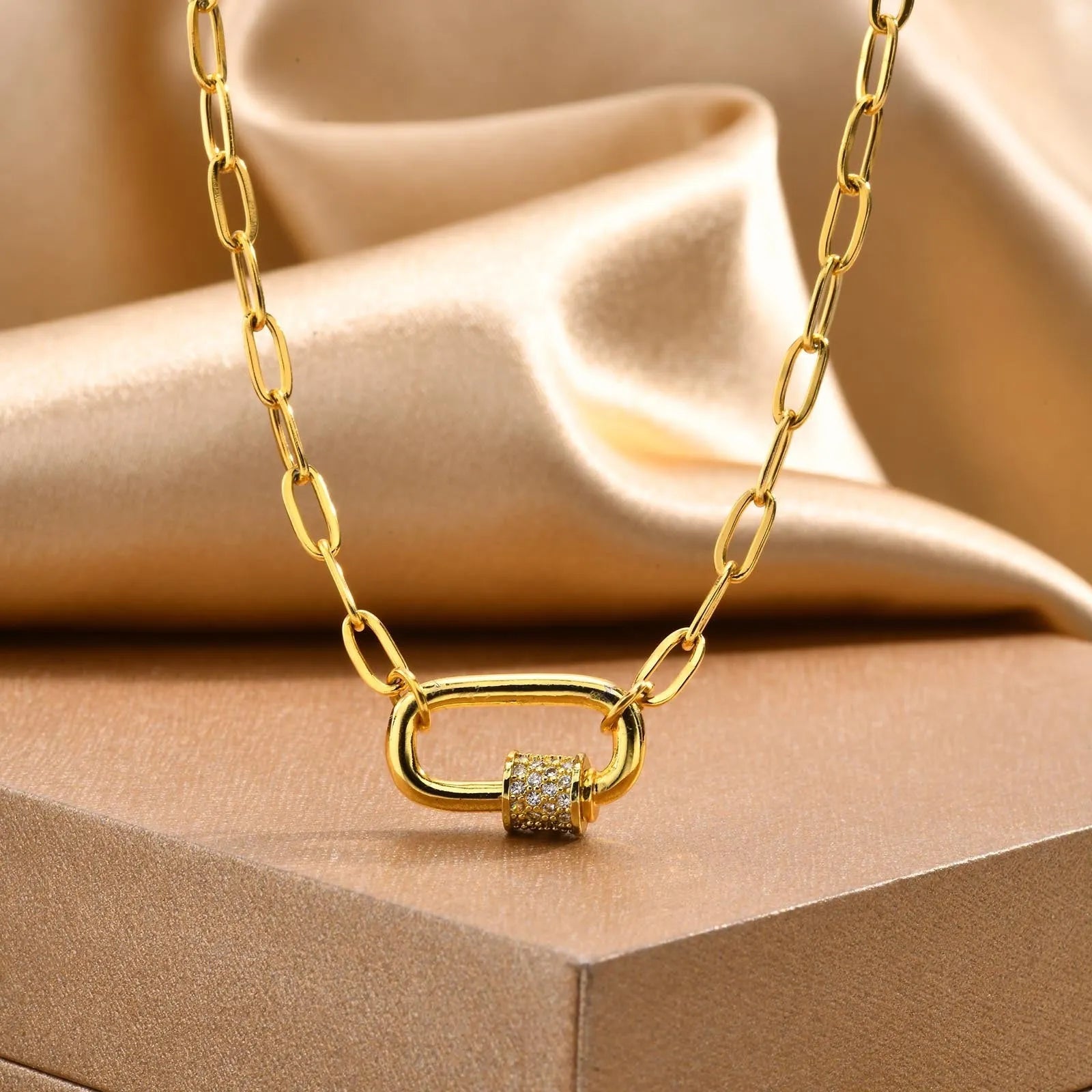 Gold electroplated stainless steel small square chain necklace with oval zircon pendant on a light background