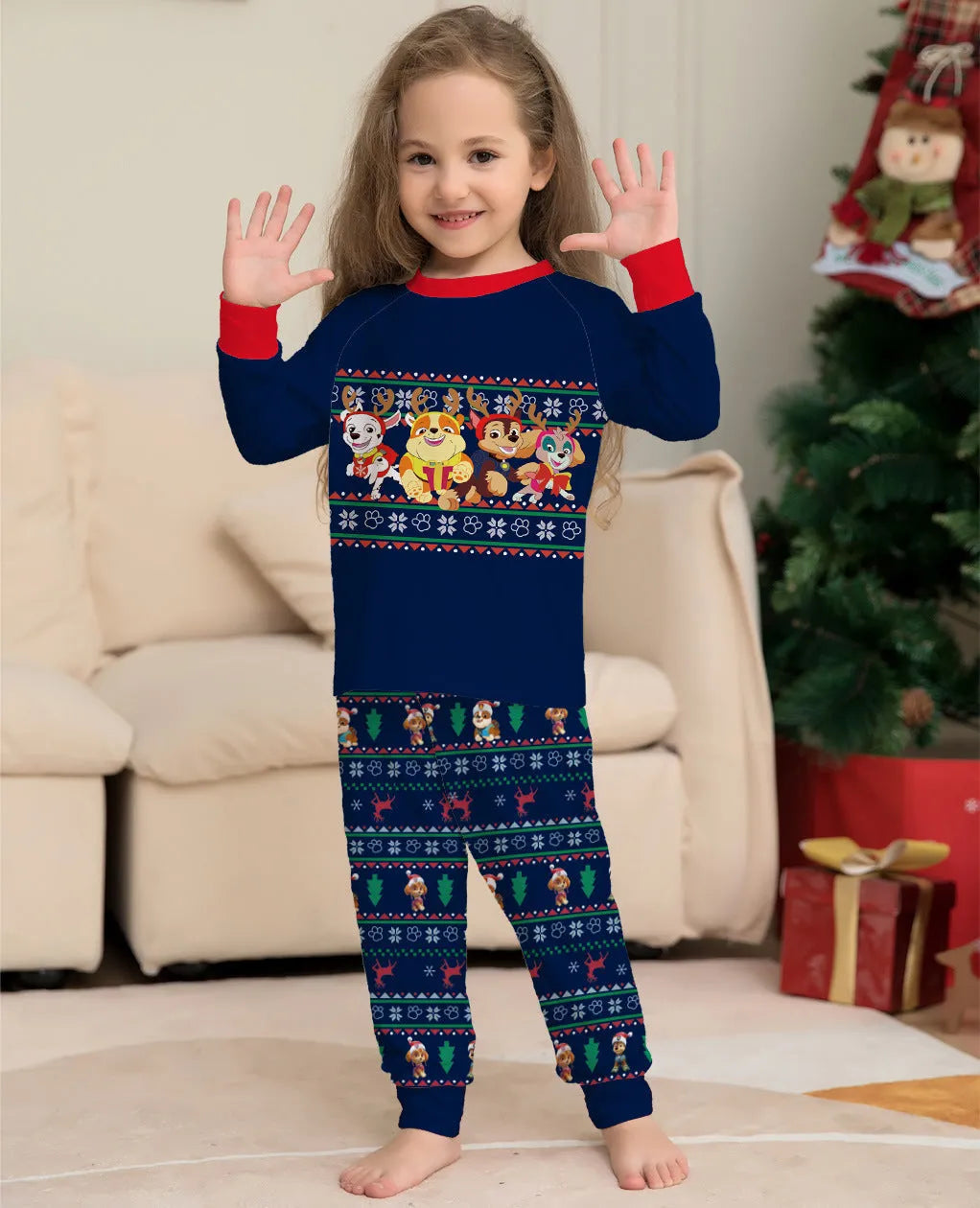 Family wearing matching red plaid Christmas pajamas with deer motif, including parents, children, and a dog.