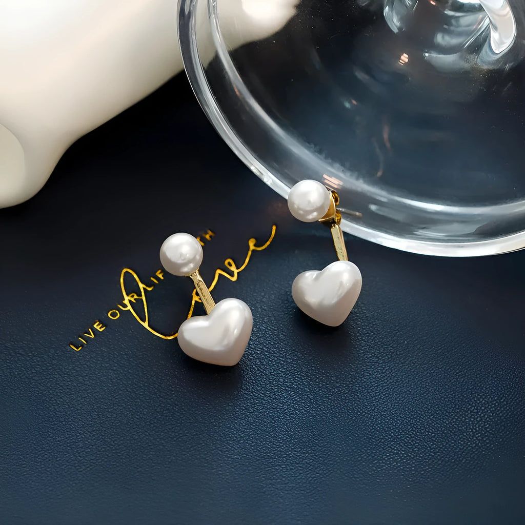 Close-up of women's heart-shaped alloy stud earrings with inlaid pearl-like artificial gems on a white background.
