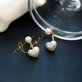 Close-up of women's heart-shaped alloy stud earrings with inlaid pearl-like artificial gems on a white background.