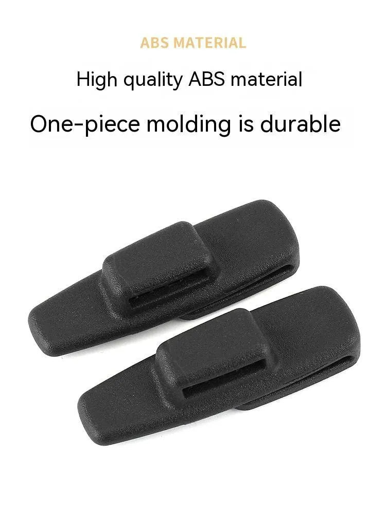 Two black ABS plastic universal car seat belt stopper clips on a white background.
