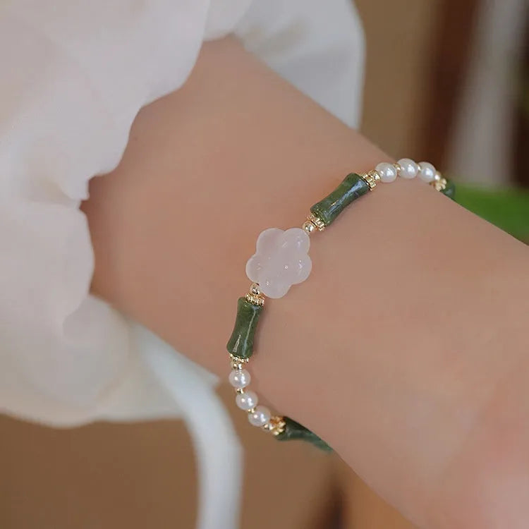 Close-up of a handcrafted Chinese antique style bracelet with bamboo joint design, featuring Hetian jade and 4mm shell pearls with copper details.