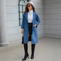 Blue waist-tie mid-length women's wool coat with long sleeves, pockets, and patchwork details