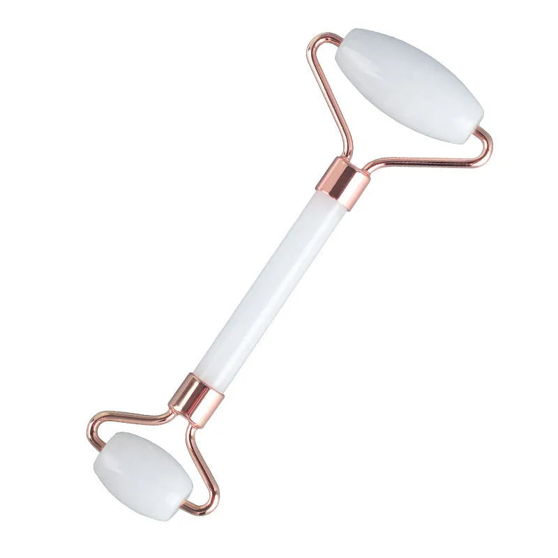 White jade facial roller and gua sha scraping board set on a table.