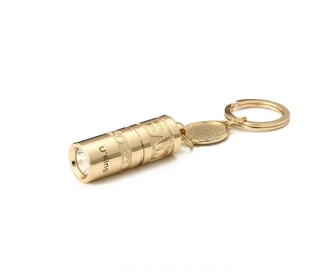 Gold-coloured zinc alloy mini LED flashlight on a keyring for outdoor and emergency use.