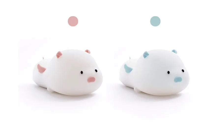 Pink silicone night light in the shape of a sleeping pig on a table.