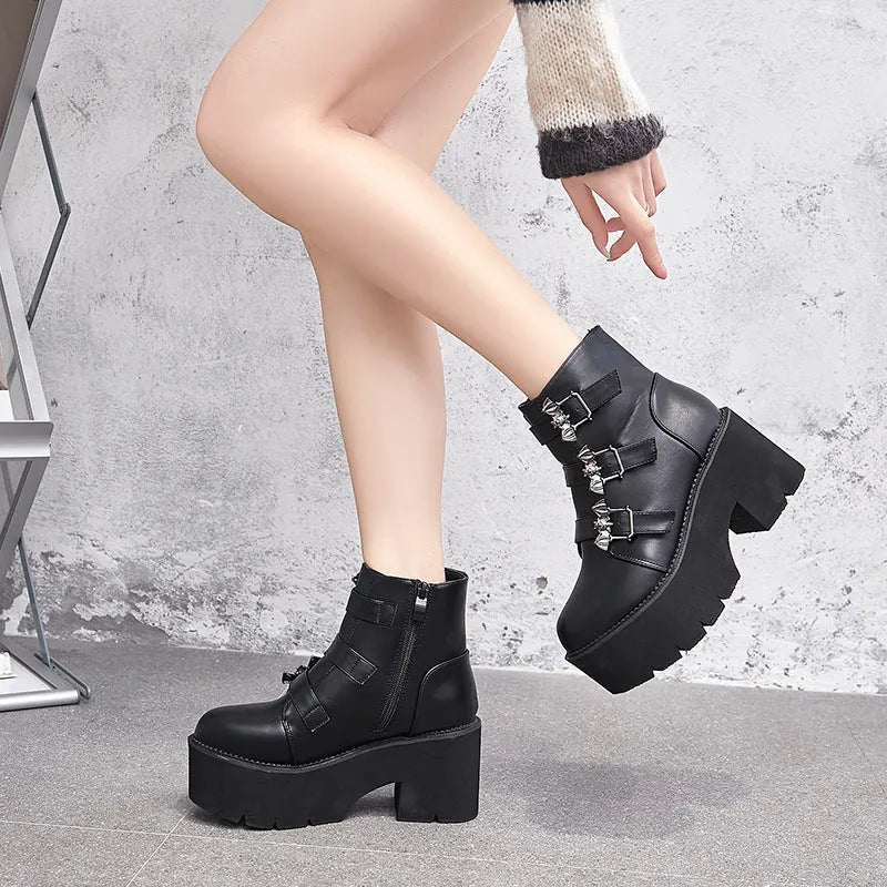Black women's punk ankle boots with metal bat buckle and thick platform sole.