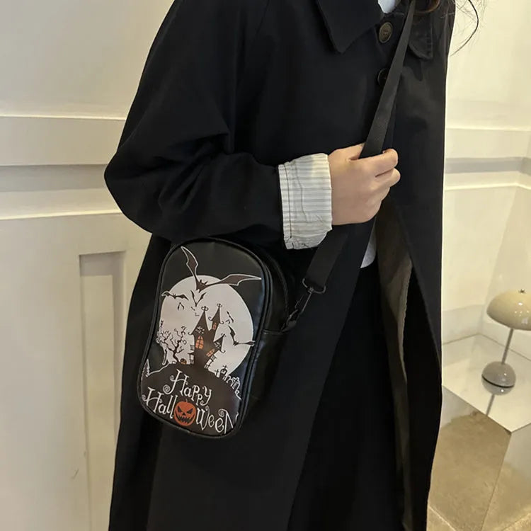 Black Halloween crossbody bag with orange pumpkin, white ghost, and black bat graffiti print, shown on adjustable strap.