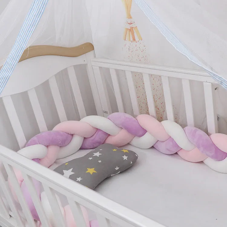 Braided knot style crib bumper in spandex velvet, wrapped around white cot rails in a nursery.