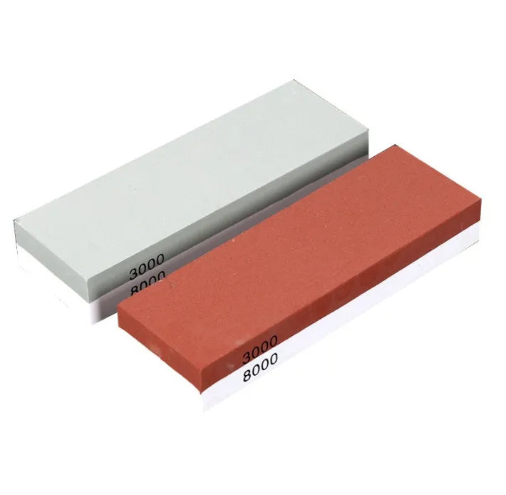 Red and white dual-grit kitchen whetstone on a bamboo base with sharpening accessories.