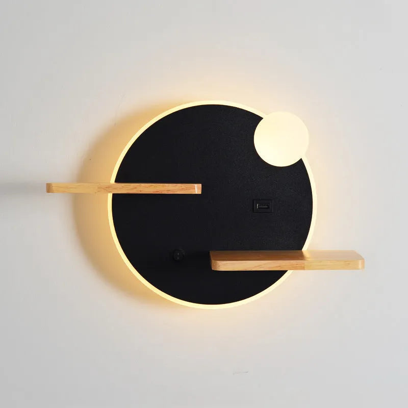 Black round bedside lamp with USB charging port on a wooden nightstand.