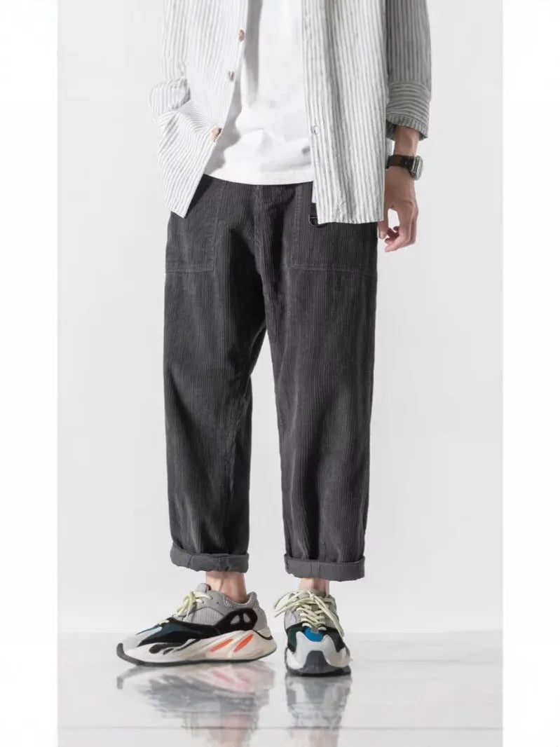 Man wearing loose tapered straight-leg trousers in a dark grey colour with wide legs.