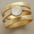 Gold-plated titanium steel geometric ring with a micro-inlaid white chalcedony stone.
