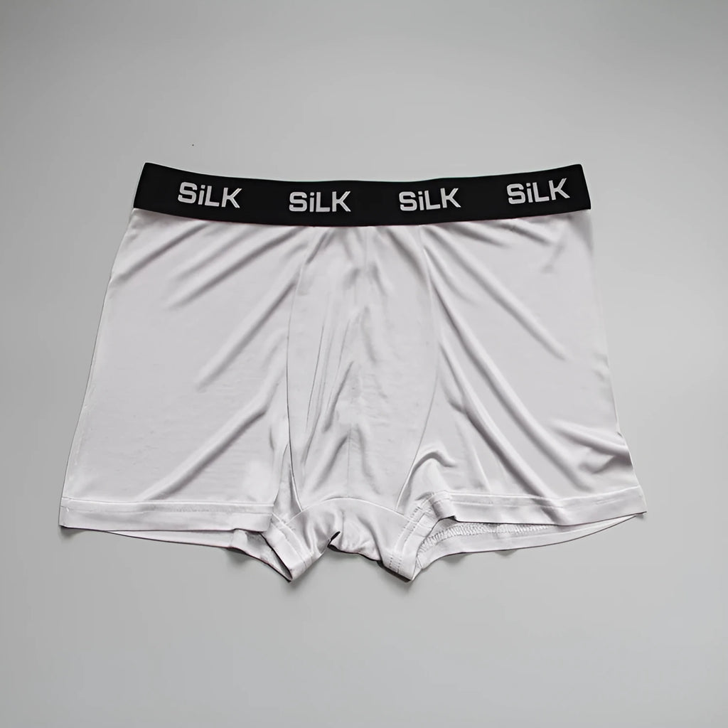 Men's loose fit silk shorts in navy blue on a mannequin, showing mid-waist design.
