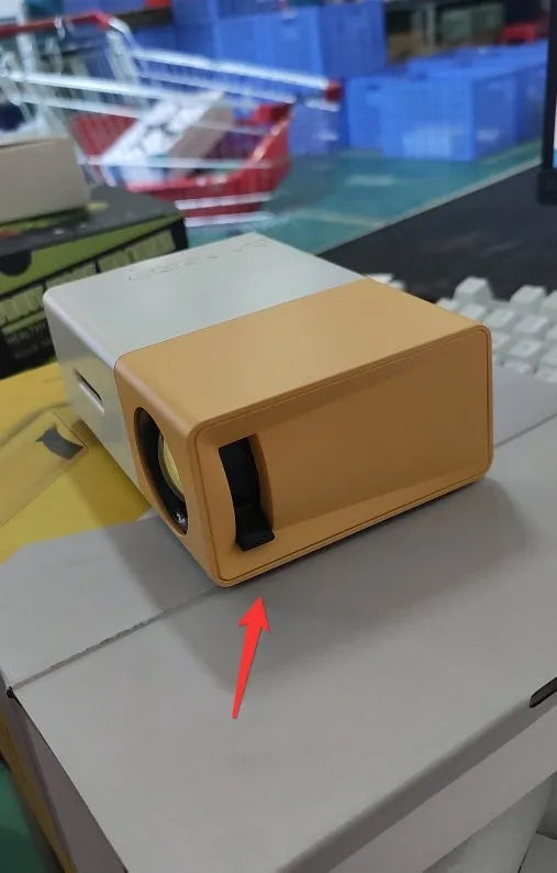 Mini LED projector YG300 in white and yellow, with lens and ventilation grilles, on a table