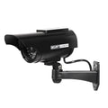 Solar powered fake security camera in black with solar panel on top and red LED light