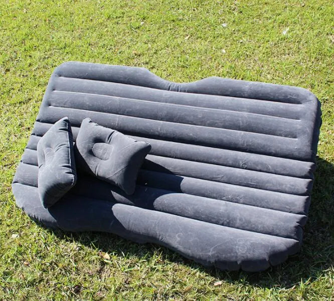 Inflatable car bed with flocked surface and two pillows, laid out in a vehicle.