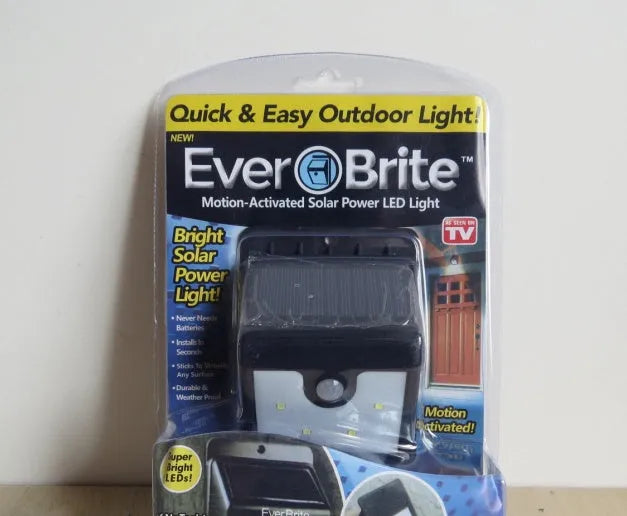 Tall outdoor solar light with four LEDs and an adjustable panel on a pole in a garden