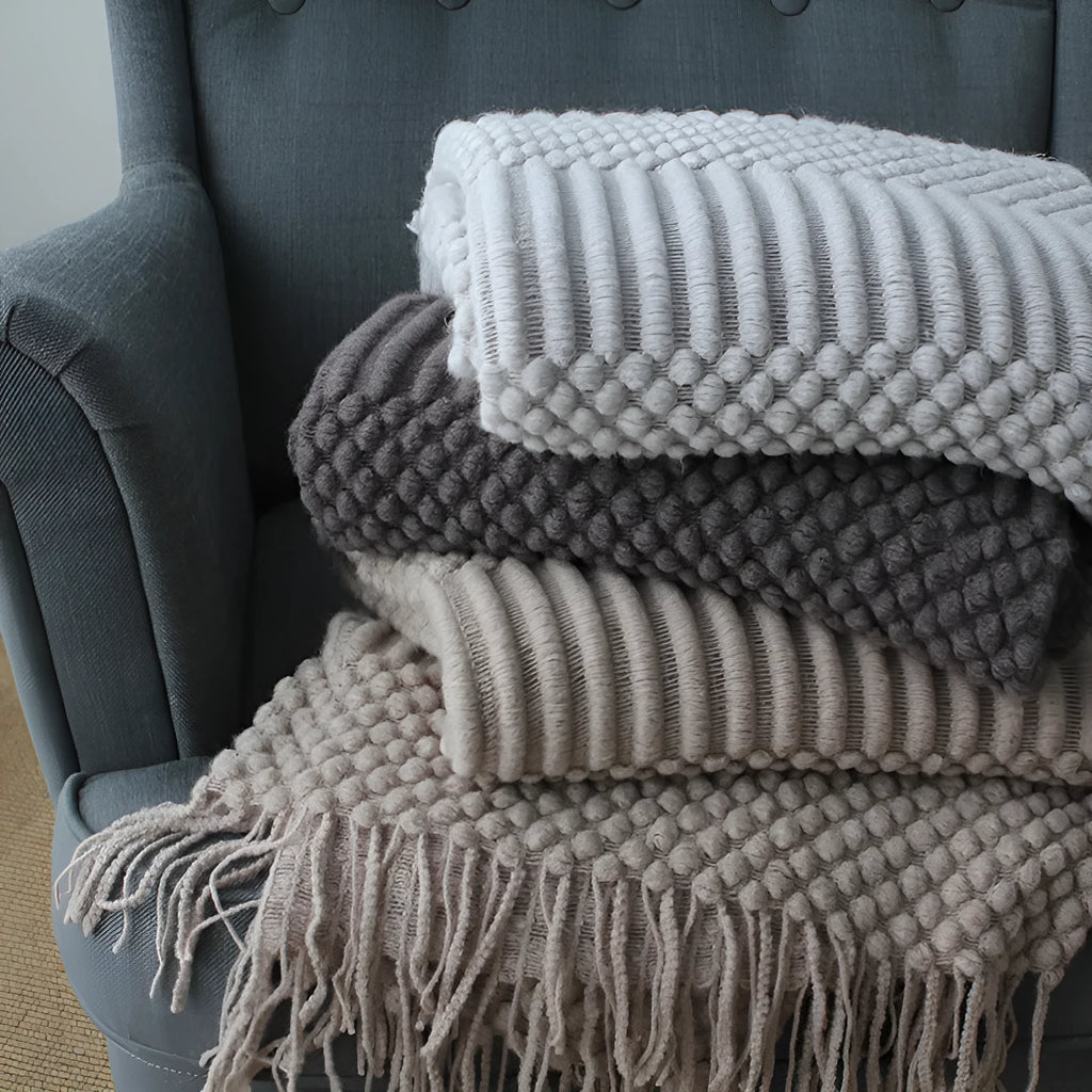 Small light grey polyester fleece blanket folded on a sofa